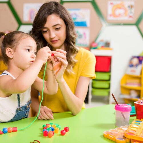 teacher and child working with beads